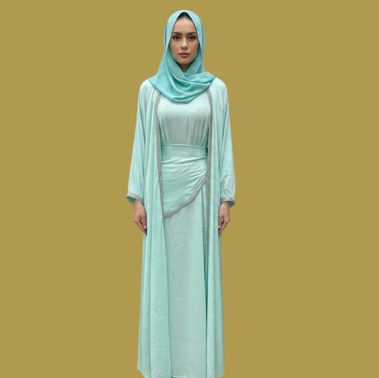 Model wearing a Shuto Modest Boutique Deena Elegant Abaya 4-piece set in mint green silk with silver trim detailing.